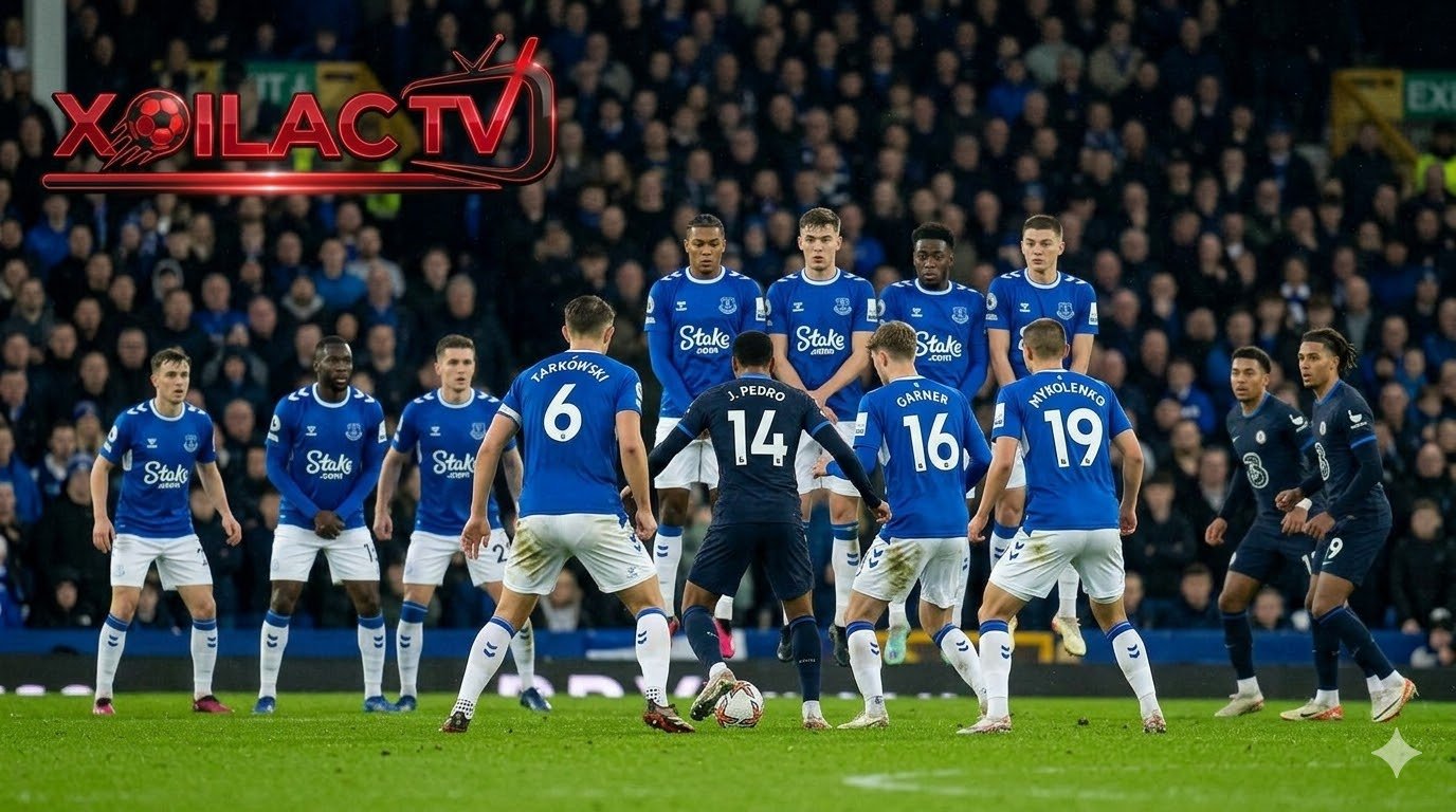Góc quay trên cao chiến thuật trận Everton vs Chelsea với cầu thủ Everton bị marqués giữa sân và logo XOILAC TV lớn màu đỏ. Điểm số là 1-1.